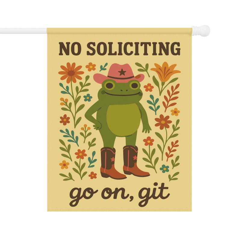 May include: A decorative garden flag with a cartoon frog wearing a cowboy hat and boots. The flag has the text "NO SOLICITING" and "go on, git" in brown lettering. The background is a light yellow with floral accents.