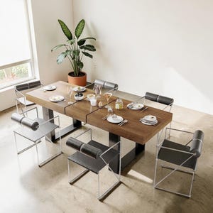 May include: A modern dining table with a dark wood surface and black metal base, set for a meal. Six chairs with black seats and chrome frames surround the table. A large potted plant sits nearby, adding a touch of greenery.