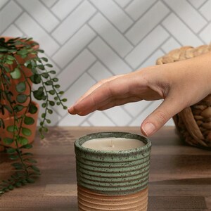 Reusable ceramic candle jar in green and tan with a hand-poured non-toxic soy wax refill. Ideal for eco-conscious gift giving.