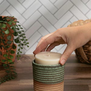 Eco-friendly refillable candle in a green and tan ceramic jar with a no-mess soy wax refill. Perfect for modern sustainable living.