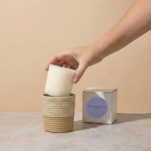 A lavender scented soy wax candle refill being placed into a handmade, ceramic refillable candle jar