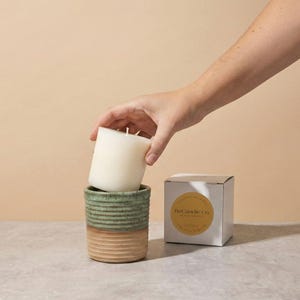 A blood orange scented soy wax candle refill being placed into a handmade, ceramic refillable candle jar