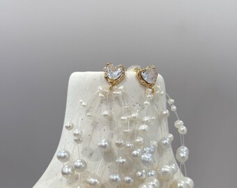May include: A pair of gold earrings with a heart-shaped crystal and a cascade of white pearls.