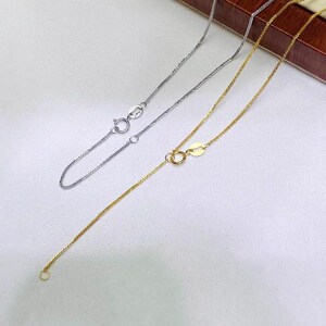 May include: Two delicate wheat chain necklaces, one in a silver tone and one in a gold tone. Each necklace features a small, circular spring ring clasp mechanism for secure fastening, showcasing a fine, woven metal link design throughout.