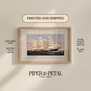 May include: Framed print of a vintage sailing ship with billowing white sails on a wavy sea. The print is in a light wood frame with a checkered background. Text on the image includes "PRINTED AND SHIPPED" and "PIPER & PETAL vintage designs."