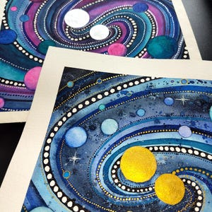 Könnte beinhalten: Eine weiße Keramik-Tasse mit schwarzem Henkel und dem Text "But First, Coffee" in fetter, schwarzer Schrift. Die Tasse steht vor einem verschwommenen Hintergrund, der eine gemütliche Umgebung andeutet.