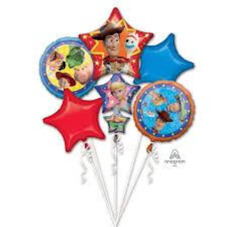 May include: A cluster of Toy Story-themed balloons. The balloons include star and circular shapes in red, blue, and gold, featuring images of Woody, Buzz Lightyear, and other characters. The balloons are attached to white sticks with ribbons.
