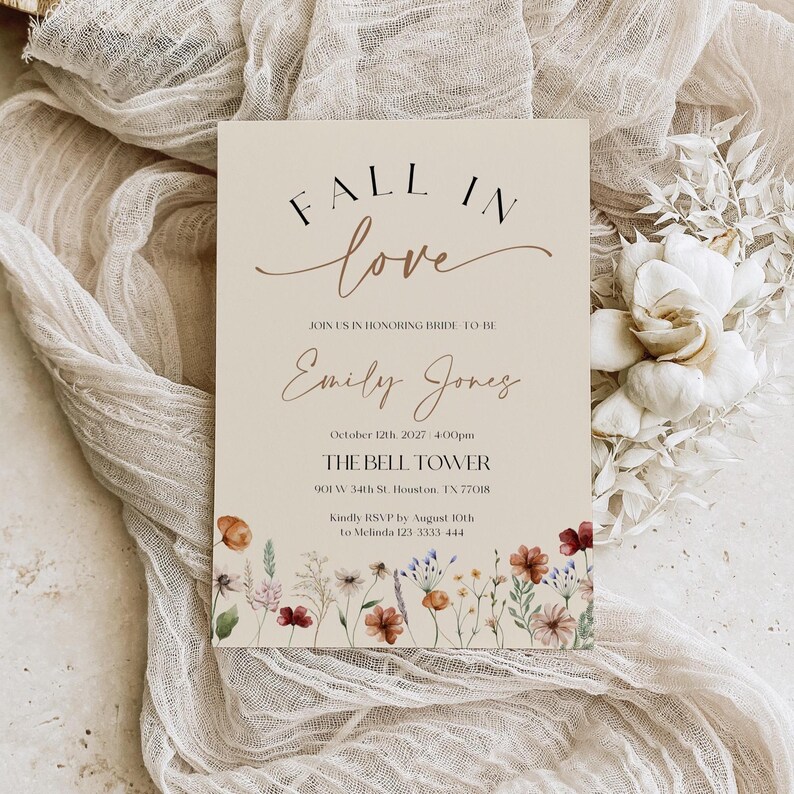Fall in Love" bridal shower invitation with modern calligraphy, autumn wildflowers border, and minimalist neutral background.