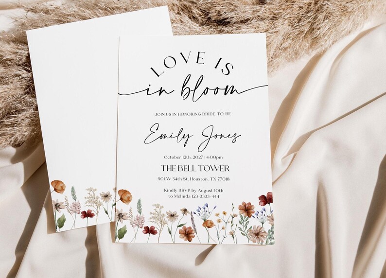 Minimalist bridal shower invitation with “Love is in Bloom” script, soft white background, and a border of colorful wildflowers in rustic tones.