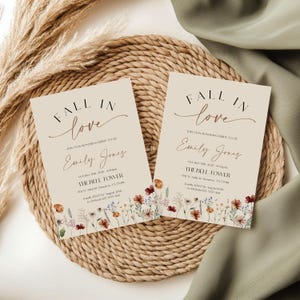Fall in Love" bridal shower invitation with modern calligraphy, autumn wildflowers border, and minimalist neutral background.