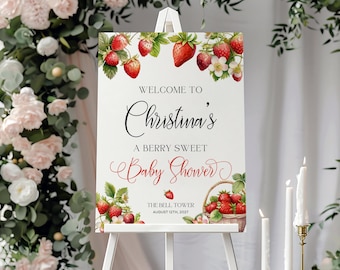 May include: A white sign with a watercolor illustration of strawberries and greenery. The text reads "Welcome to Christina's A Berry Sweet Baby Shower The Bell Tower August 12th, 2027".