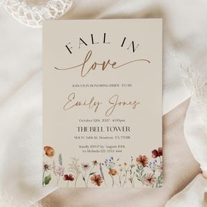Fall in Love" bridal shower invitation with modern calligraphy, autumn wildflowers border, and minimalist neutral background.
