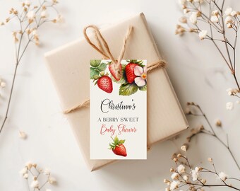May include: A white gift tag with a watercolor illustration of strawberries and flowers. The text on the tag reads "Christina's A Berry Sweet Baby Shower".