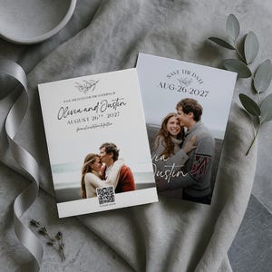 May include: Two white wedding announcement cards with photos of a couple. The cards read "Save the Date" and include the names "Olivia and Justin" and the date "August 26, 2027". One card has a QR code.
