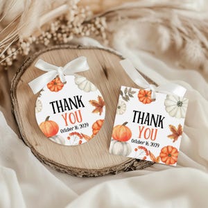 Może przedstawiać: Dwie jesienne etykiety na prezenty z białymi wstążkami. Jedna jest okrągła, druga prostokątna. Obie zawierają napis "THANK YOU" w kolorze czarnym i pomarańczowym z datą "October 16, 2029". Dynie, liście i jagody zdobią etykiety.