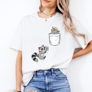 Raccoon and Trash Can T-Shirt, Funny Climbing Animal Illustration, Playful Cartoon Design with Pocket Look, Crewneck Unisex Shirt
