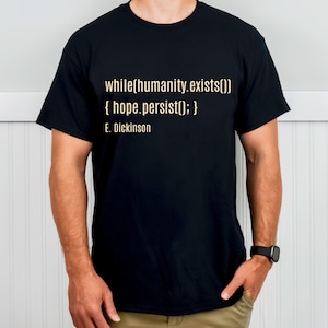 Könnte beinhalten: Schwarzes T-Shirt mit dem Zitat "while(humanity.exists()) { hope.persist(); } E. Dickinson" in hellbeiger Schrift. Das T-Shirt hat einen Rundhalsausschnitt.