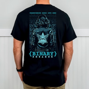 Könnte beinhalten: Schwarzes T-Shirt mit einem grafischen Design auf der Rückseite. Das Design zeigt eine Person in einer Lederjacke mit einem Auge in einem Dreieck, Flügeln und dem Text "BINARY BREAKER". Über der Person steht der Text "TRANSFORMING ZEROS INTO ONES".