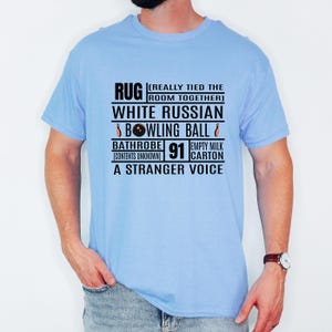 Könnte beinhalten: Hellblaues T-Shirt mit schwarzem Aufdruck. Der Aufdruck enthält die Wörter "RUG", "WHITE RUSSIAN", "BOWLING BALL", "BATHROBE", "91", "EMPTY MILK CARTON" und "A STRANGER VOICE".