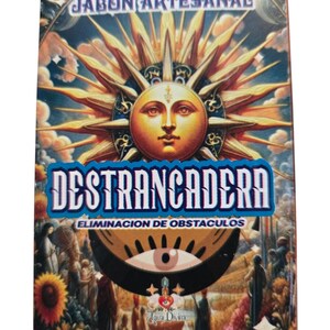 May include: A yellow and blue box with a sun and eye design. The box has the text "Jabón Artesanal Destrancadera Eliminación de Obstáculos" and "Agua Divina".
