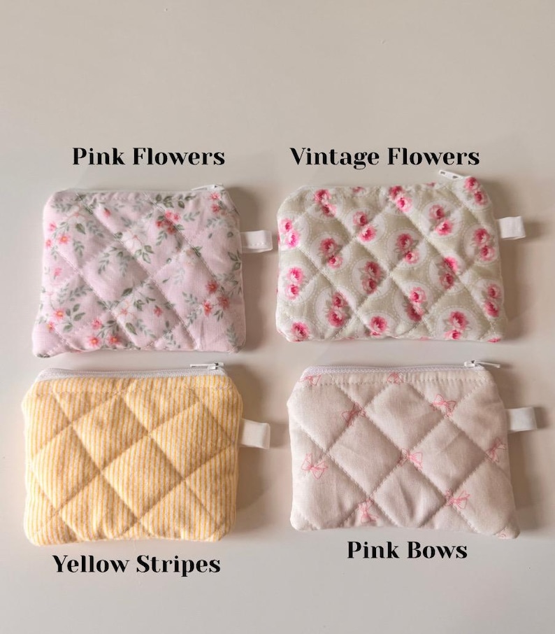 May include: Four quilted zipper pouches with different patterns. The pouches are pink with pink flowers, pink with vintage flowers, yellow with yellow stripes, and pink with pink bows. The pouches are all the same size and shape.