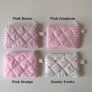 May include: Four quilted zipper pouches with different pink and white patterns. The pouches are labeled "Pink Roses", "Pink Gingham", "Pink Design", and "Dainty Fruits".