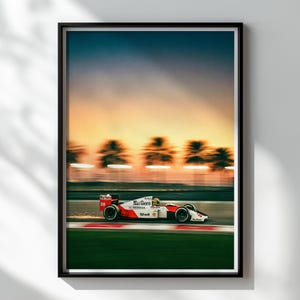 May include: Framed print of a Formula 1 race car in motion, featuring a red, white, and black color scheme with the "Marlboro" logo. The background shows a blurred sunset with palm trees, creating a sense of speed and motion.