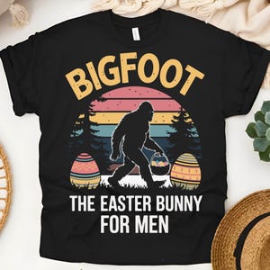 Könnte beinhalten: Schwarzes T-Shirt mit einer Retro-Grafik von Bigfoot, der Ostereier hält. Der Text lautet "Bigfoot, der Osterhase für Männer".