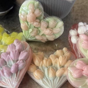 May include: Heart-shaped soaps with a tulip design. The soaps are wrapped in clear plastic and feature a variety of colours, including pink, peach, yellow, and white. The tulips are arranged in a bouquet pattern.