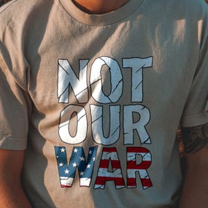 Maglietta con messaggio contro la guerra – Maglietta "Not Our War" – Maglietta di protesta per attivisti – Maglietta con grafica patriottica – Maglietta sulla libertà di parola – Maglietta con dichiarazione sulla bandiera degli Stati Uniti