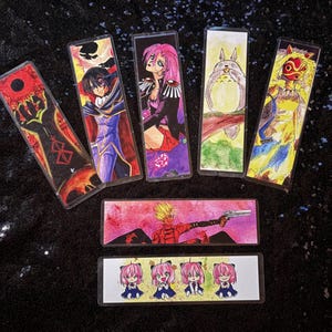 May include: A collection of rectangular anime-themed bookmarks. Each bookmark features a different character illustration, with vibrant colors and detailed artwork. The bookmarks are made of a clear, glossy material.