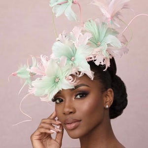 Peut inclure: Un accessoire de tête décoratif composé d'un arrangement de plumes vert menthe doux et rose pâle en forme de fleurs. Le design comprend des tiges fines et courbées ainsi que de petits accents centraux, créant une structure superposée.