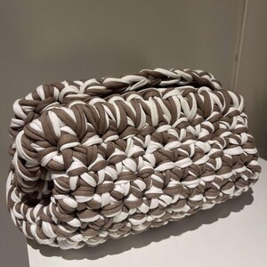 May include: A brown and white crocheted bag with a textured design.