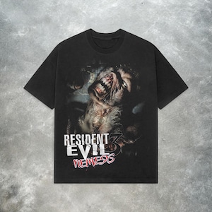 Könnte beinhalten: Schwarzes T-Shirt mit einer detaillierten Grafik eines Monsters mit scharfen Zähnen und dem Text "RESIDENT EVIL 3 NEMESIS" in Weiß und Rot. Das Shirt hat einen Rundhalsausschnitt und kurze Ärmel.