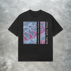May include: Black t-shirt featuring the text "nine inch nails" in white on the right side and "pretty hate machine" on the left. The center graphic has red and blue hues.