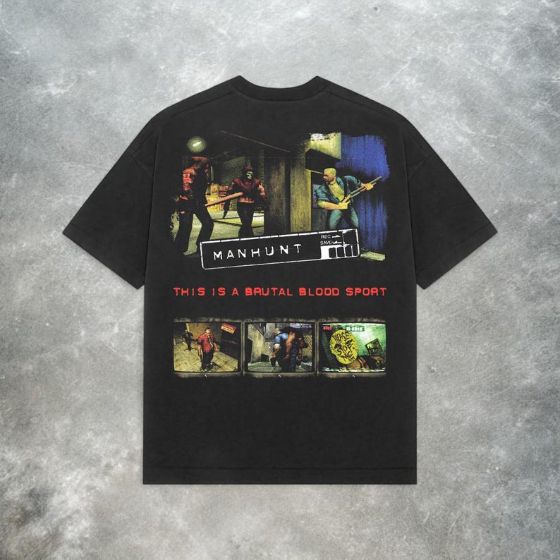 Peut inclure: T-shirt noir avec un imprim&eacute; graphique d'un personnage de jeu vid&eacute;o tenant une arme. Le texte "Manhunt" et "This is a brutal blood sport" est imprim&eacute; sur le t-shirt.