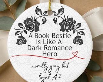 May include: Round white ceramic ornament with black floral accents and the text "A Book Bestie Is Like A Dark Romance Hero." The ornament also includes the phrases "morally gray but loyal AF" in a script font.