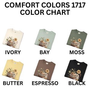 Vintage-style t-shirt featuring a stacked pile of antique books surrounded by detailed sunflowers and botanical floral accents. Perfect for book lovers and readers who enjoy a cozy, literary aesthetic. The design is printed on a soft neutral tee, ideal for fall fashion or as a thoughtful book club gift.