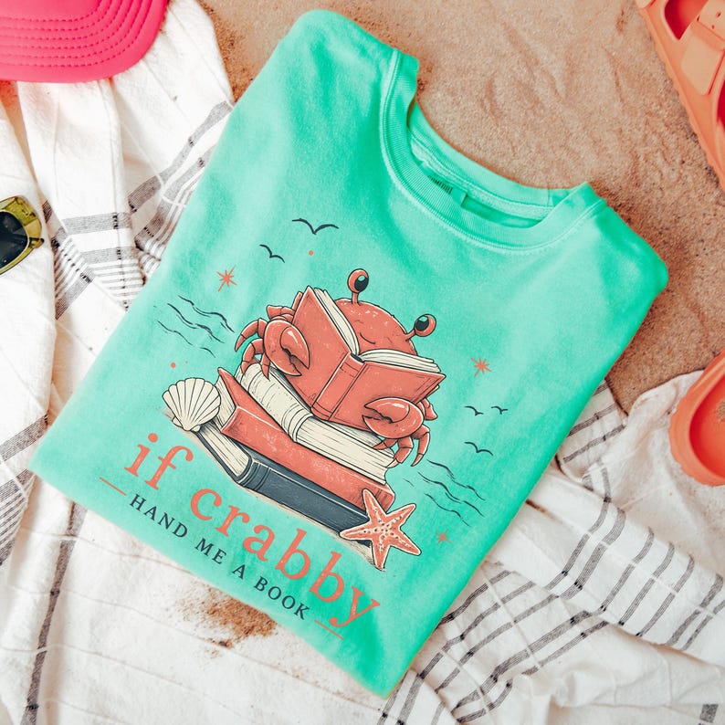 Cute beach reader shirt with crab illustration reading a book beside ocean waves