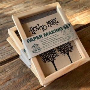 Könnte beinhalten: Ein Satz aus zwei Holzrahmen mit Maschensieben zur Papierherstellung. Die Rahmen sind übereinander gestapelt und haben ein braunes Papieretikett mit der Aufschrift "How to Make Paper Making Set".