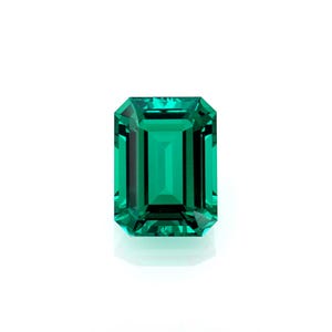 May include: A vibrant, emerald-cut gemstone with a deep green hue. The rectangular stone has a faceted surface that reflects light, creating a brilliant sparkle. The gem is set against a clean white background.