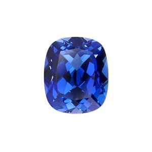May include: A cushion-cut gemstone, displaying a rich, deep blue colour. The facets of the gem catch the light, producing a sparkling effect. The shape is a rounded square, set against a white backdrop.