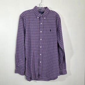 Op de afbeelding: Een overhemd met lange mouwen in een paars en wit ruitpatroon. Het overhemd heeft een button-down kraag, een klein geborduurd logo op de borst en een klassieke pasvorm. Het hangt aan een doorzichtige plastic hanger.