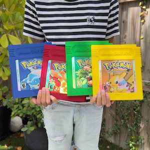 May include: Four colorful Nintendo Game Boy Pokémon game cartridges. The cartridges are blue, red, green, and yellow. Each cartridge features the Pokémon logo and game title. The blue cartridge shows a blue turtle-like creature. The yellow cartridge is a special Pikachu edition.