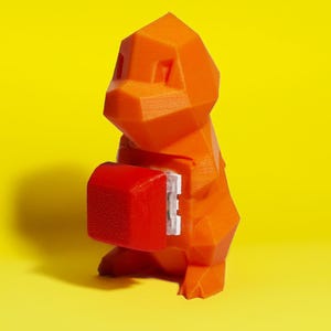 May include: An orange, geometric-shaped figure of a Charmander character, with a red rectangular component attached. The figure is set against a bright yellow background, creating a striking contrast. The design has a 3D-printed appearance.
