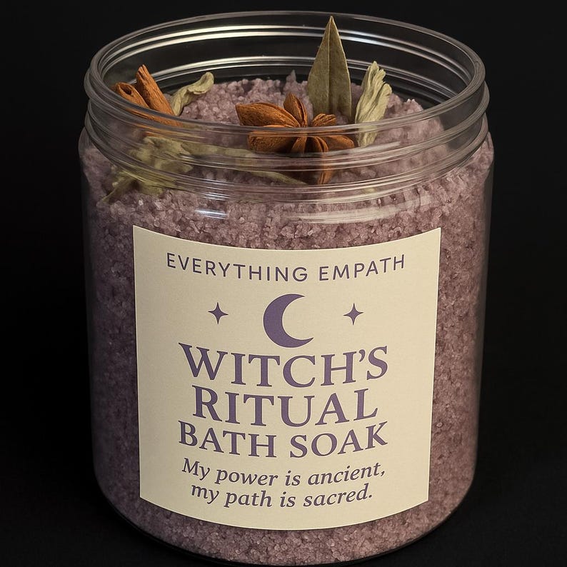 May include: A clear plastic jar filled with purple bath soak. The jar has a label that reads "Witch's Ritual Bath Soak." The soak is topped with star anise, cinnamon sticks, and other botanicals. The text on the label reads "Everything Empath, My power is ancient, my path is sacred."