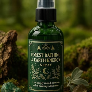 May include: A green glass spray bottle with a black cap and a label that reads "FOREST BATHING & EARTH ENERGY SPRAY." The label has gold accents and botanical illustrations. The bottle is set against a mossy background with a green stone and a clear crystal.