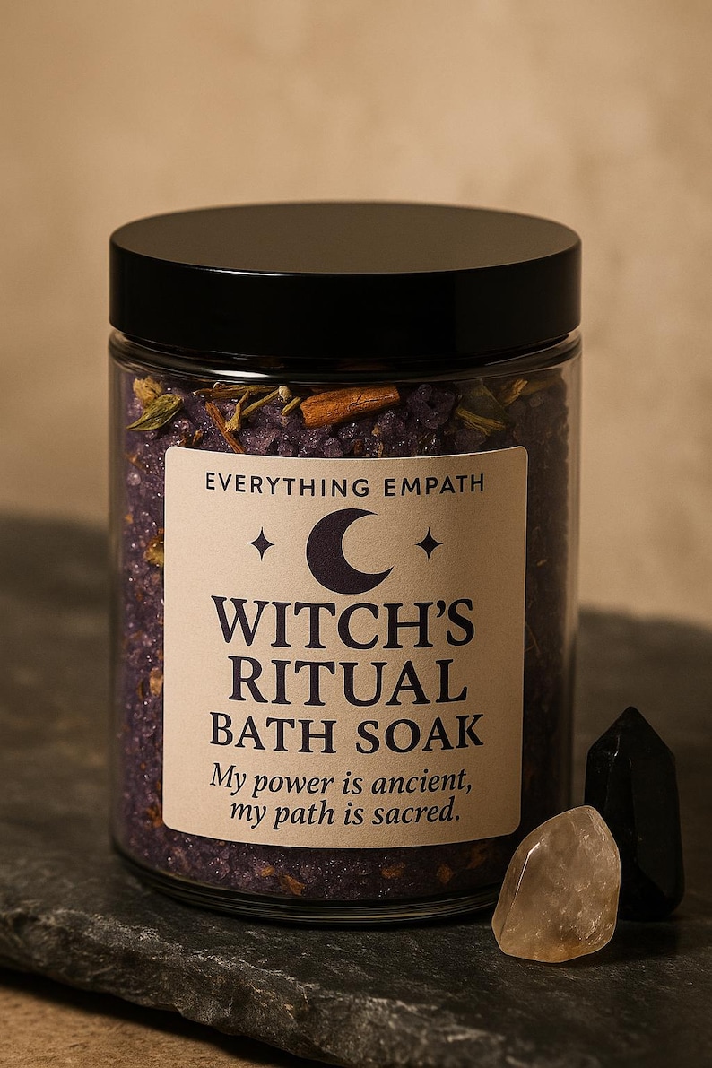 May include: A glass jar with a black lid filled with purple bath soak. The label reads "Witch's Ritual Bath Soak" with the text "My power is ancient, my path is sacred." Two crystals are next to the jar.