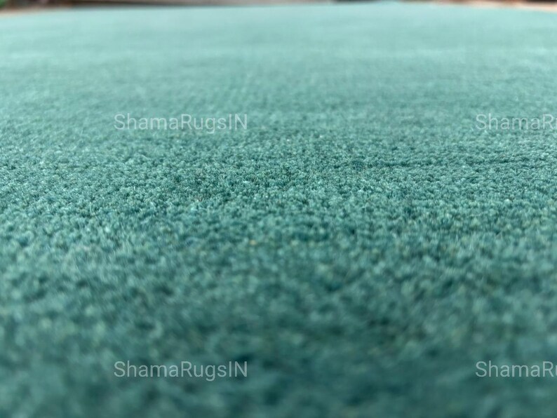 Puede incluir: Primer plano de una alfombra de color turquesa con una superficie texturizada. Las fibras de la alfombra crean una apariencia suave y afelpada. El texto "ShamaRugsIN" es visible.
