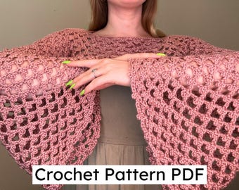 May include: A dusty rose crochet shrug with openwork detailing. The shrug features long, flared sleeves and a wide neckline. The text "Crochet Pattern PDF" is displayed at the bottom of the image. The garment is handmade.